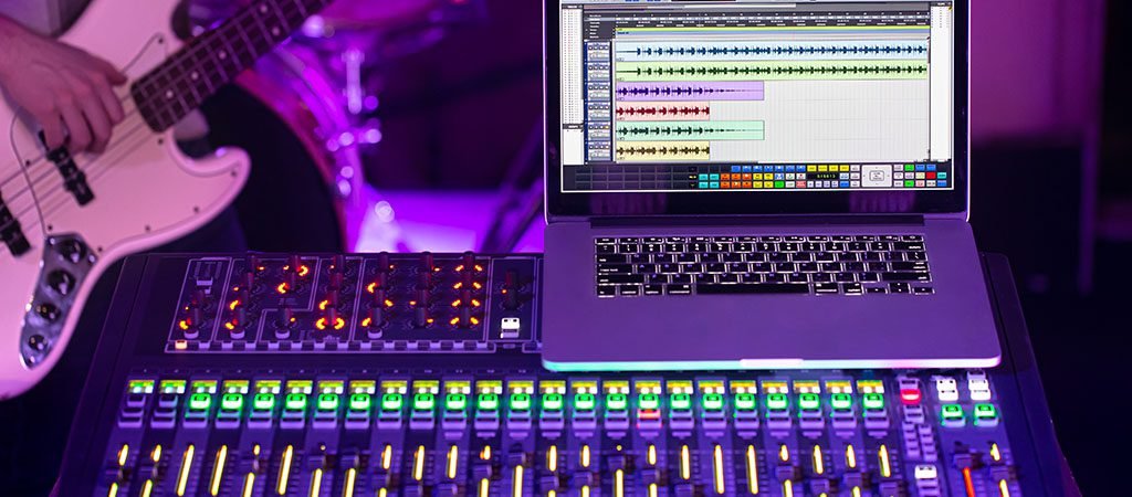 Digital mixer in a recording Studio , with a computer for recording music. On the background of a man with a bass guitar. The concept of creativity and show business.